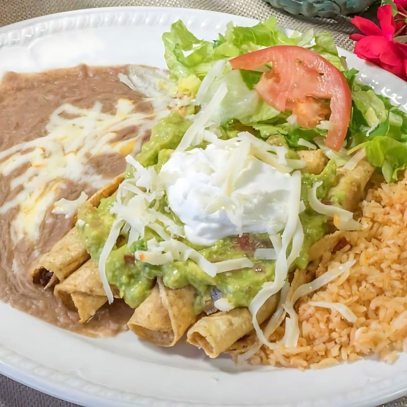 Dos Reales Latin Kitchen's Mexican taquitos with guacamole, sour cream, lettuce, tomato, rice, and beans.