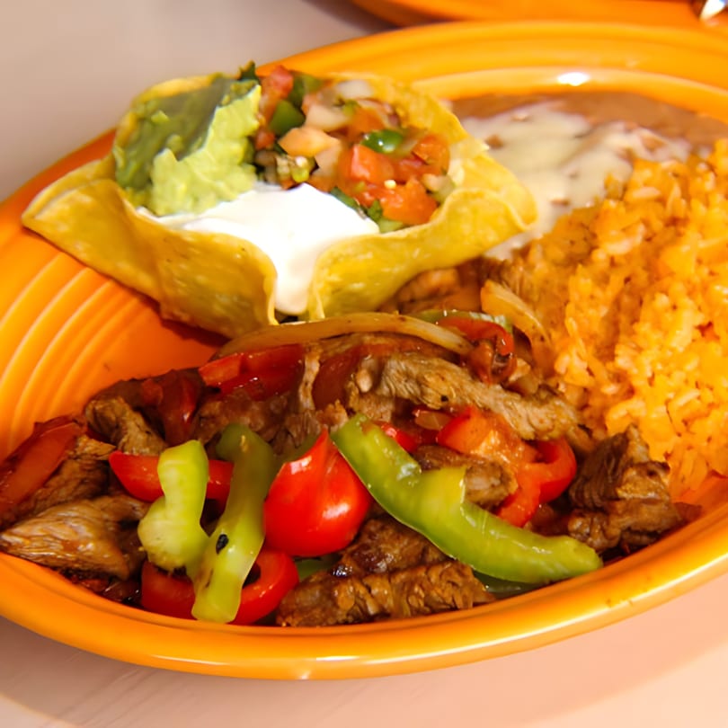 Dos Reales fajita platter with steak, peppers, onions, rice, beans, guacamole, and pico de gallo.
