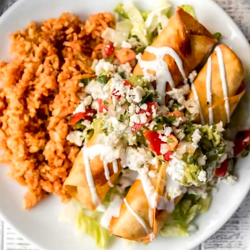 Crispy flautas drizzled with crema, topped with lettuce, pico de gallo, and cotija cheese, served with Mexican rice.